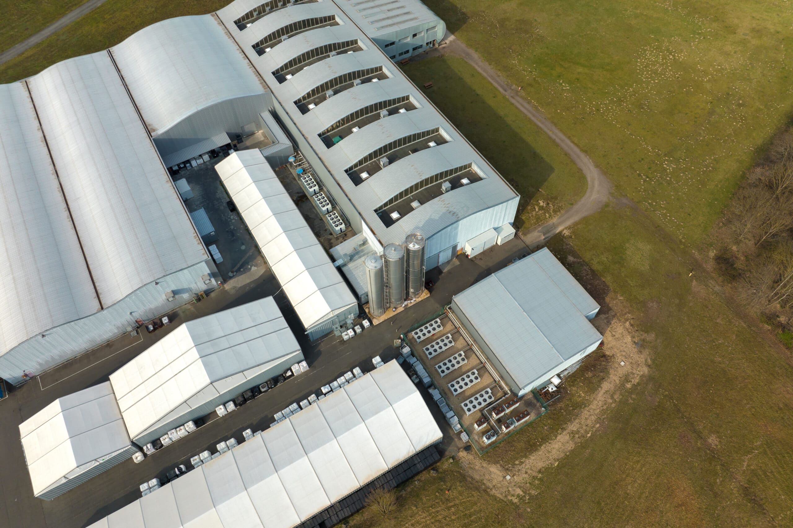 Drohnenaufnahme des Arla Foods Werks Pronsfeld – Produktionshallen mit Silos und Kühlaggregaten